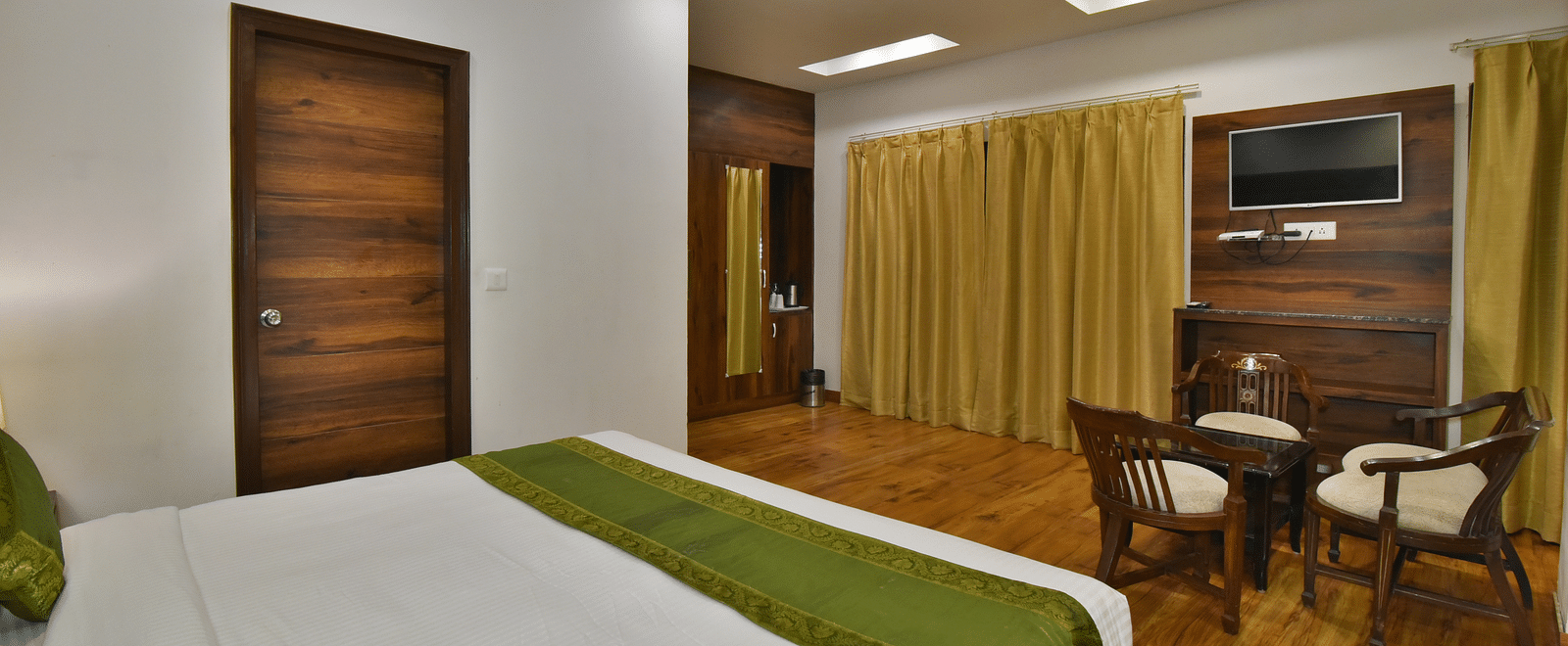 A large bed placed in front of two sofas at the Luxury Room Without Balcony at DLS Highland Resort and Spa, Mussoorie.